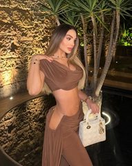 Mujer luciendo el Set Atenea Mocca, top drapeado y pantalón elegante, en ambiente nocturno sofisticado.