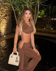 Mujer luciendo el Set Atenea Mocca, top drapeado y pantalón elegante, en ambiente nocturno sofisticado.