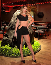 Mujer usando el Set Pecado Negro con top drapeado y falda mini, en ambiente elegante