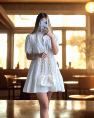 Mujer luciendo el Vestido Blanco Alexandra de Kike Rodriguez, ideal para eventos elegantes y casuales, combinado con un bolso blanco y zapatillas deportivas.