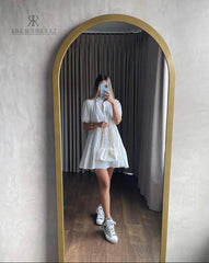Mujer luciendo el Vestido Blanco Alexandra de Kike Rodriguez, ideal para eventos elegantes y casuales, combinado con un bolso blanco y zapatillas deportivas.