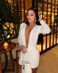 Mujer de pie con el Vestido Furia blanco, mostrando detalles drapeados y bolso estructurado.