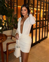 Mujer de pie con el Vestido Furia blanco, mostrando detalles drapeados y bolso estructurado.