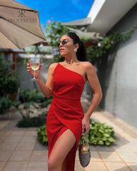 Modelo luciendo un vestido rojo de un solo hombro con abertura en la pierna de KIKE RODRIGUEZ. Vestido de noche sofisticado ideal para eventos y fiestas, destacando por su estilo moderno y elegante.