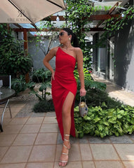 Modelo luciendo un vestido rojo de un solo hombro con abertura en la pierna de KIKE RODRIGUEZ. Vestido de noche sofisticado ideal para eventos y fiestas, destacando por su estilo moderno y elegante.
