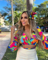 Mujer vistiendo una blusa crop top multicolor con mangas largas y estampado geométrico, perfecta para un look vibrante y colorido. Disponible en KIKE RODRIGUEZ.