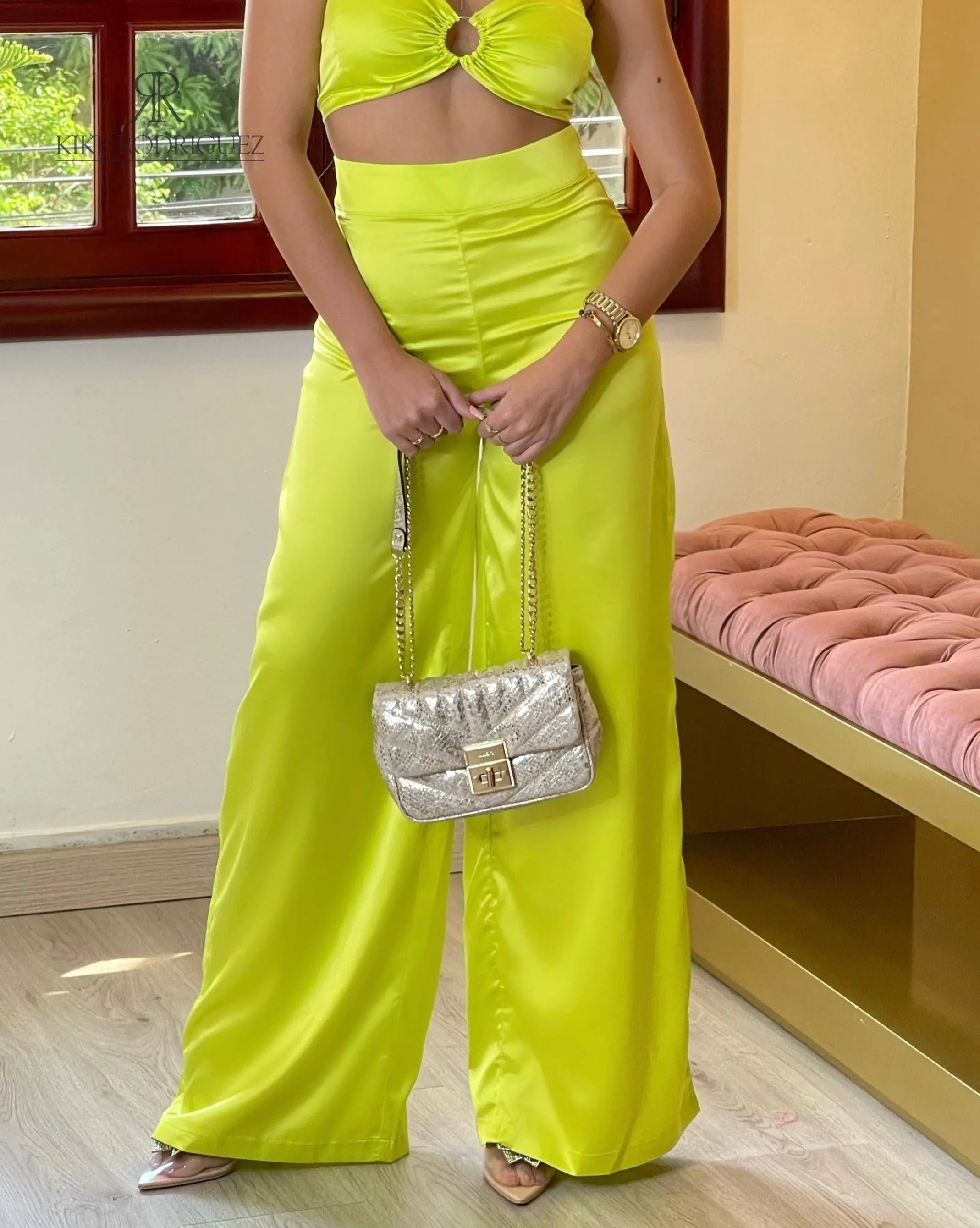 Mujer vistiendo un top verde con detalle de aro de KIKE RODRIGUEZ, complementado con pantalones del mismo tono. Perfecto para destacar en eventos y ocasiones especiales.