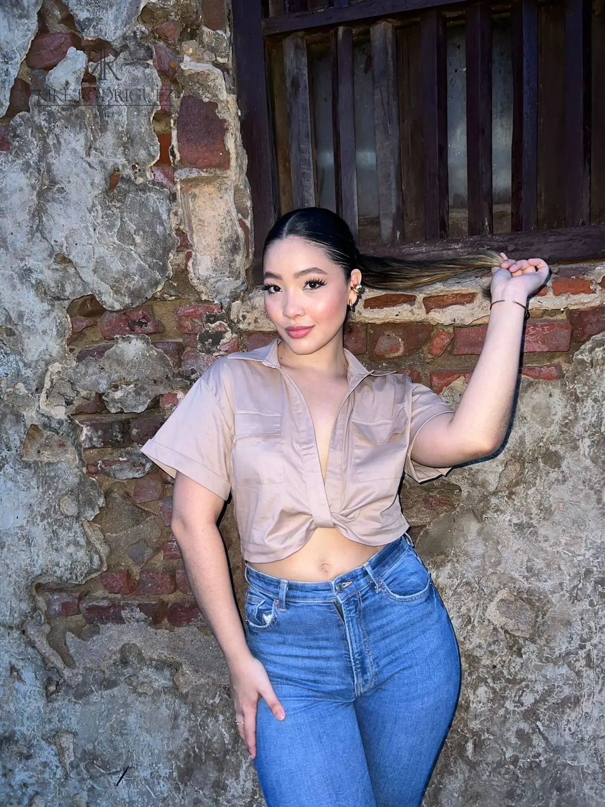 Mujer vistiendo una blusa crop nude con mangas cortas, perfecta para un look elegante y moderno. Ideal para cualquier ocasión. Disponible en KIKE RODRIGUEZ.