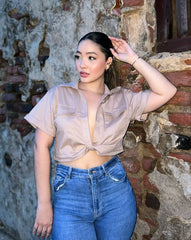 Mujer vistiendo una blusa crop nude con mangas cortas, perfecta para un look elegante y moderno. Ideal para cualquier ocasión. Disponible en KIKE RODRIGUEZ.