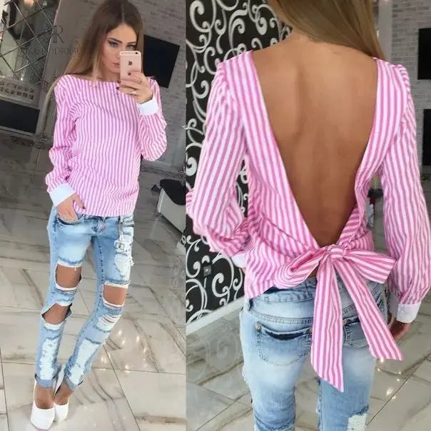 Mujer con blusa rosa con espalda descubierta disfrutando de una vista panorámica. Blusa ideal para un look casual y sofisticado. Disponible en KIKE RODRIGUEZ.