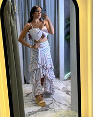 Mujer vistiendo una falda larga asimétrica a rayas multicolor con volantes, posando en un ambiente moderno y elegante.