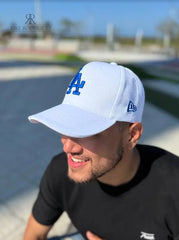 Hombre usando una gorra blanca de Kike Rodriguez con logo azul de Los Angeles Dodgers, combinada con gafas de sol y camiseta negra, ideal para un look deportivo y elegante