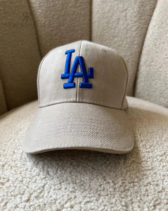Gorra beige de Kike Rodriguez con logo azul de Los Angeles Dodgers, ideal para un look casual y moderno, perfecta para combinar con cualquier outfit diario