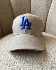 Gorra beige de Kike Rodriguez con logo azul de Los Angeles Dodgers, ideal para un look casual y moderno, perfecta para combinar con cualquier outfit diario