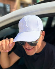 Hombre usando una gorra blanca de Kike Rodriguez con logo blanco de los New York Yankees, combinada con gafas de sol y camiseta negra para un look casual y moderno