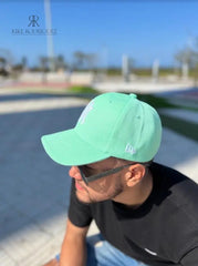 Hombre usando una gorra verde menta de Kike Rodriguez con logo blanco de los New York Yankees, combinada con gafas de sol y camiseta negra para un look moderno y fresco