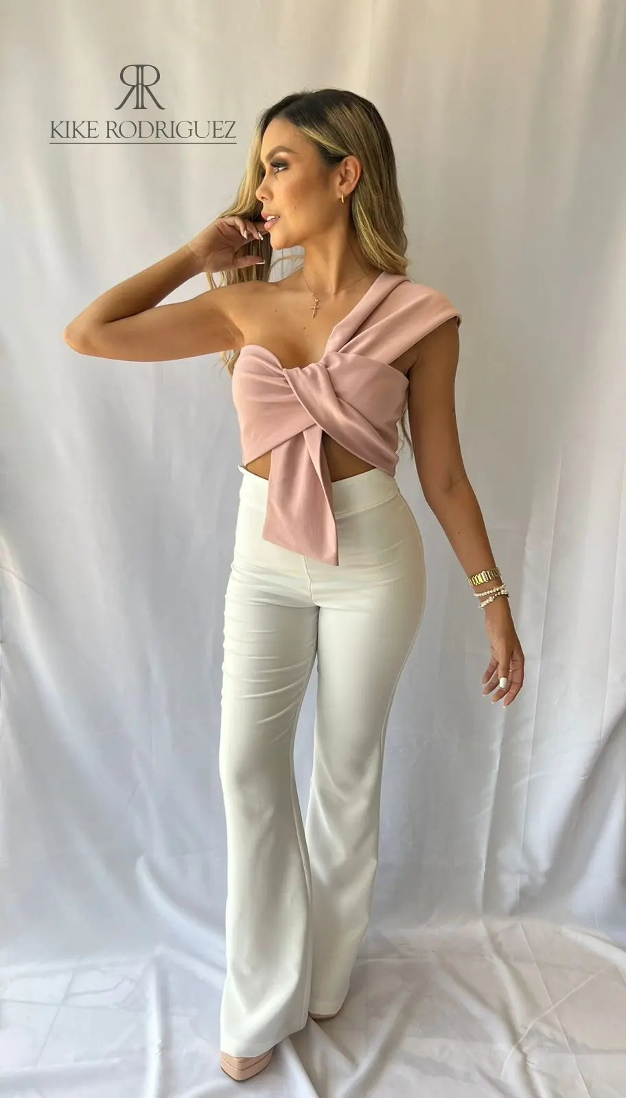 Mujer con top asimétrico rosa con lazo frontal, ideal para ocasiones especiales con un estilo elegante y sofisticado.