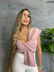 Mujer con top asimétrico rosa con lazo frontal, ideal para ocasiones especiales con un estilo elegante y sofisticado.