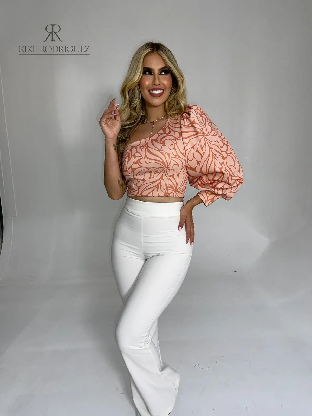Mujer luciendo un top asimétrico con estampado floral en tonos rosados, con una manga larga abullonada, ideal para un look elegante y moderno.