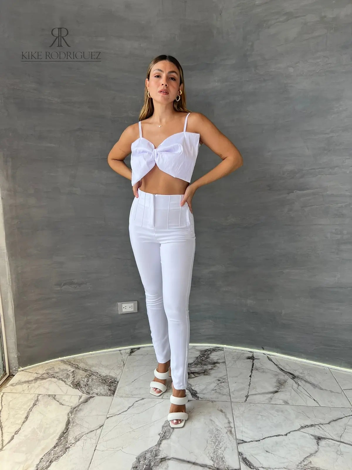Mujer luciendo un top blanco con lazo frontal, ideal para un look elegante y sofisticado. Perfecto para cualquier ocasión especial.