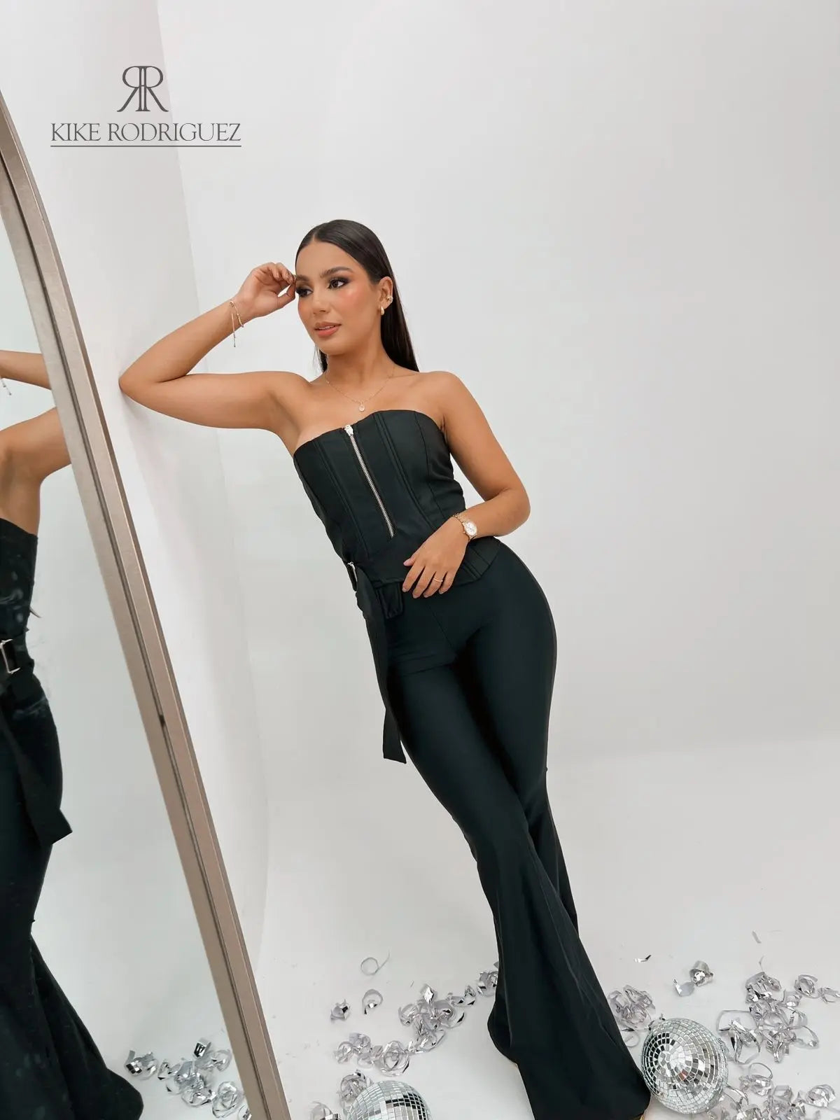 Top corset negro con cremallera frontal, ideal para un look sofisticado y moderno, combinado con pantalones ajustados para resaltar la figura.