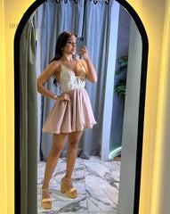 Mujer posando frente al espejo con un vestido corto de color nude, con tirantes y detalles de encaje, perfecto para eventos especiales y ocasiones elegantes.
