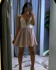Mujer posando frente al espejo con un vestido corto de color nude, con tirantes y detalles de encaje, perfecto para eventos especiales y ocasiones elegantes.