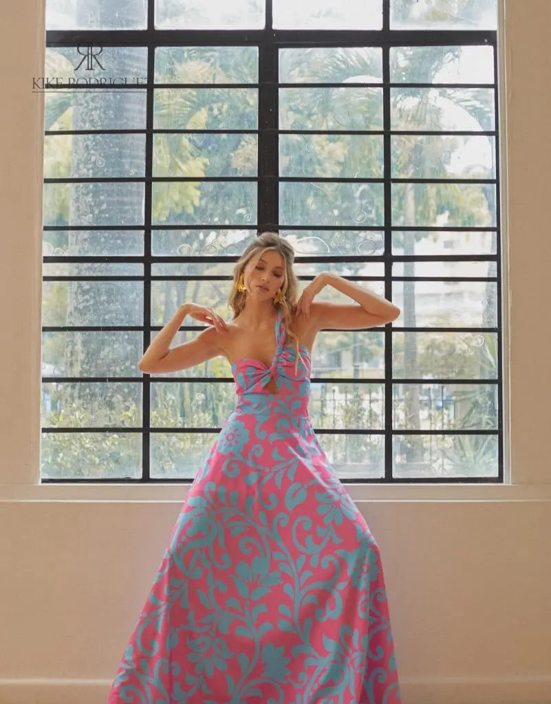 Mujer luciendo un vestido largo floral en rosa y azul de KIKE RODRIGUEZ, destacando elegancia y estilo para eventos especiales.