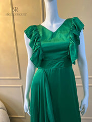 Maniquí vistiendo un elegante vestido largo de fiesta en color verde esmeralda con detalles de volantes, ideal para eventos especiales y celebraciones formales.