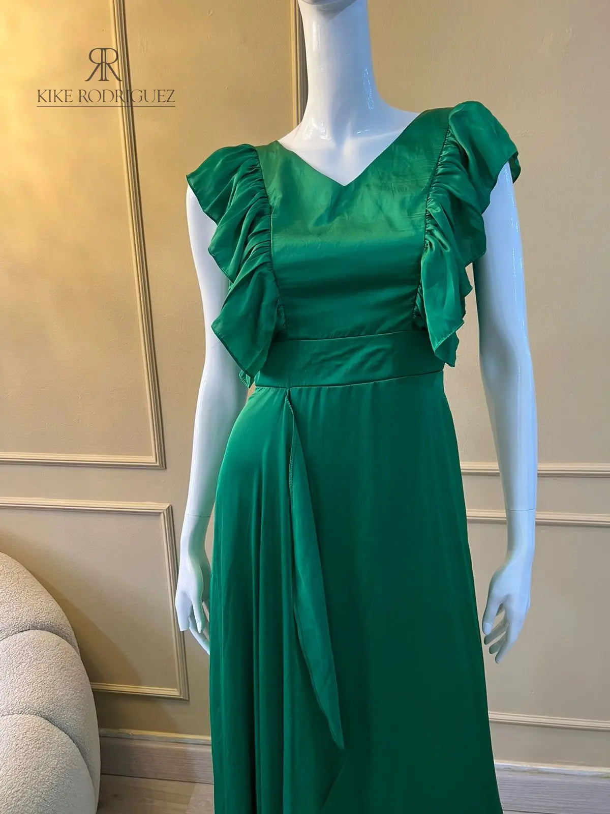 Maniquí vistiendo un elegante vestido largo de fiesta en color verde esmeralda con detalles de volantes, ideal para eventos especiales y celebraciones formales.