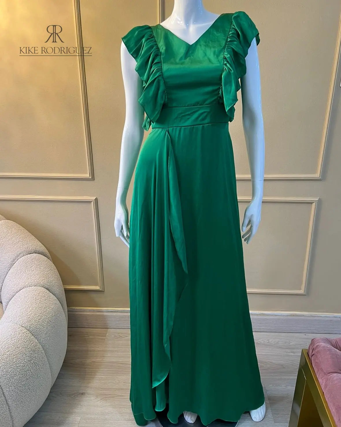 Maniquí vistiendo un elegante vestido largo de fiesta en color verde esmeralda con detalles de volantes, ideal para eventos especiales y celebraciones formales.