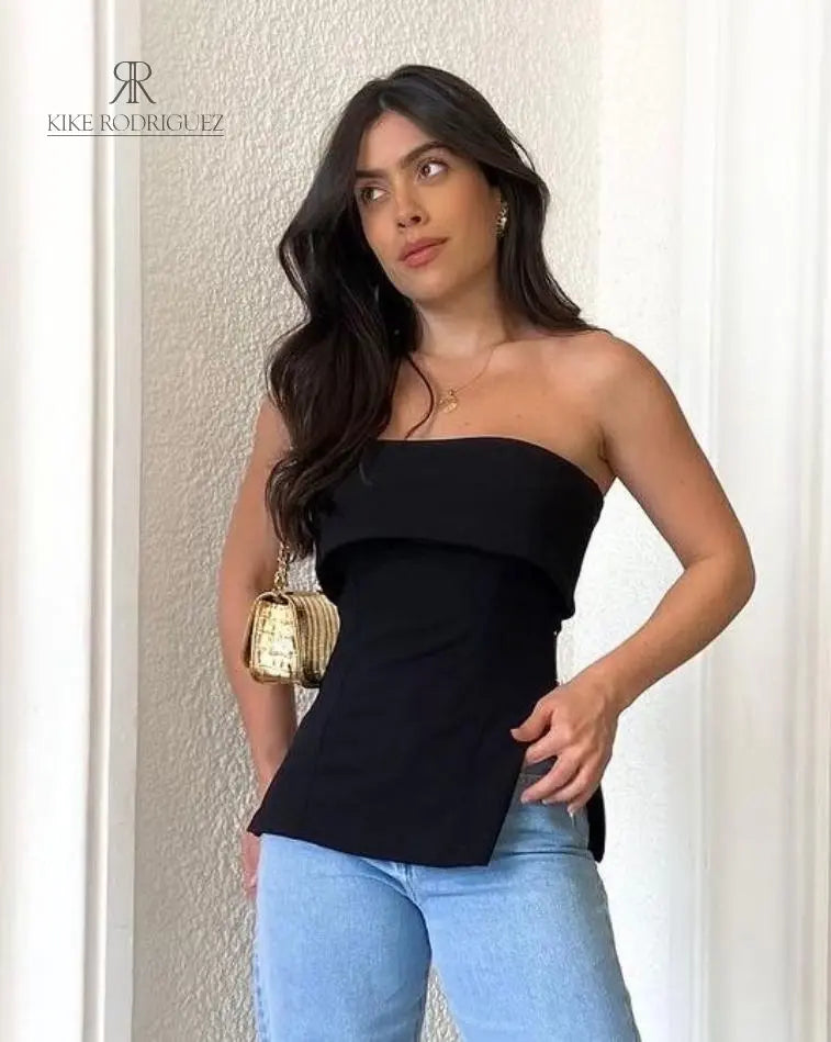 Mujer usando blusa negra strapless Paulina, combinada con jeans azules, mostrando un look elegante y moderno