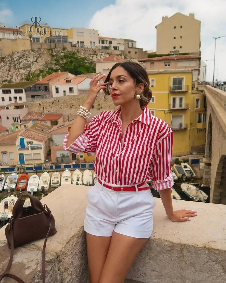 Mujer con blusa de rayas rojas y blancas, estilo casual chic, ideal para looks veraniegos.