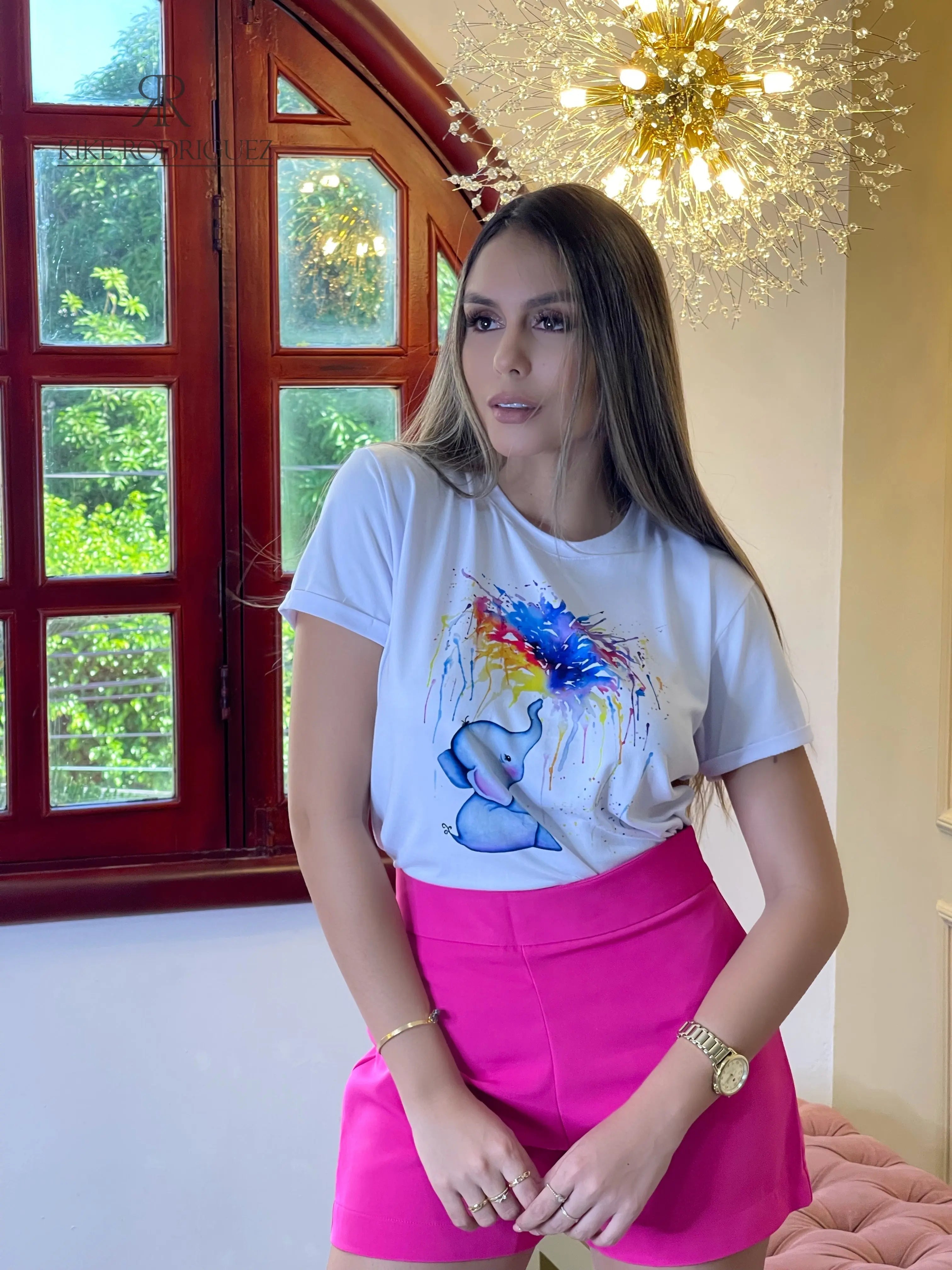 Camiseta blanca con un hermoso estampado de un elefante lanzando colores vibrantes. Disponible en promoción de 3 por $129,900 en KIKE RODRIGUEZ. Perfecta para un look creativo y tierno. ¡Ideal para cualquier ocasión!