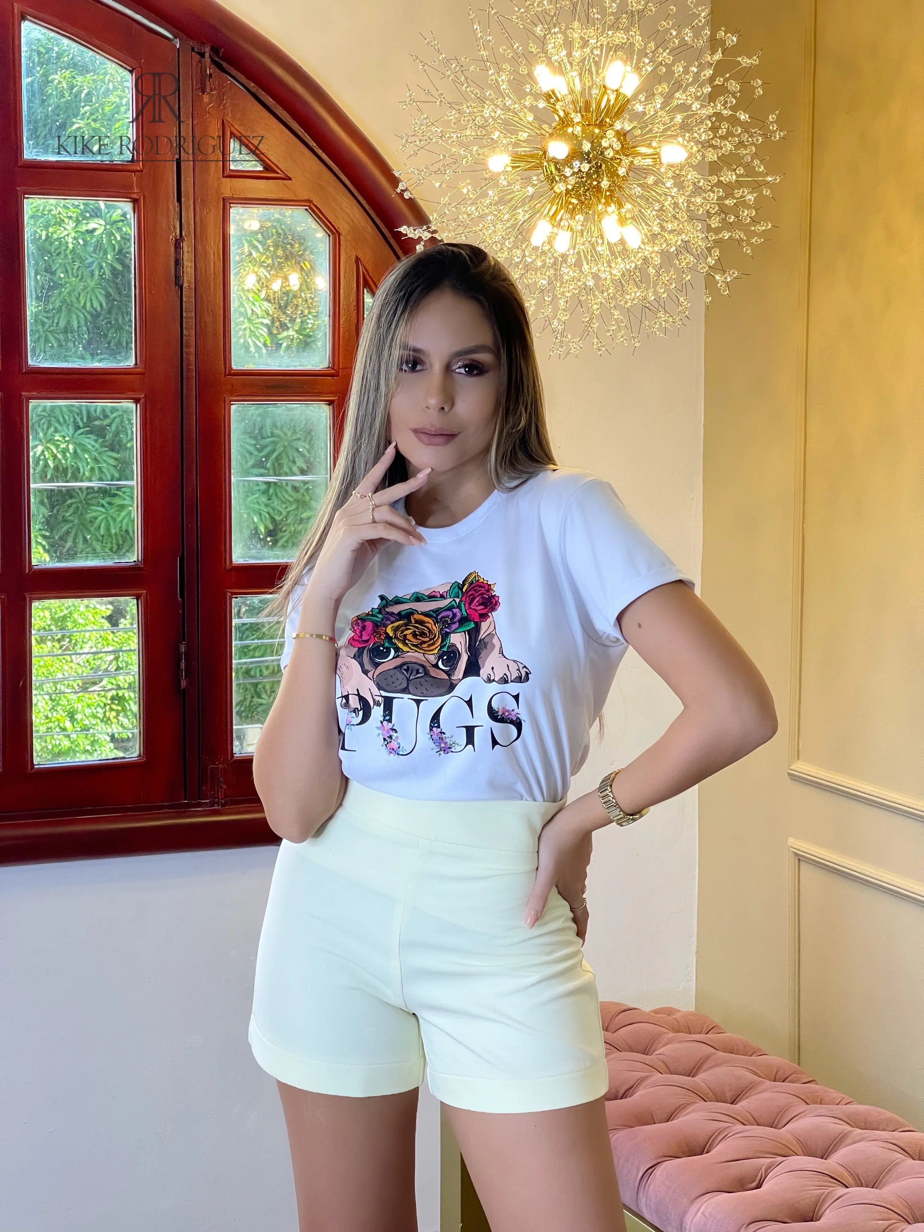 Camiseta blanca con un estampado adorable de pug con flores. Disponible en promoción de 3 por $129,900 en KIKE RODRIGUEZ. Perfecta para un look casual y divertido. ¡Ideal para amantes de los perros!